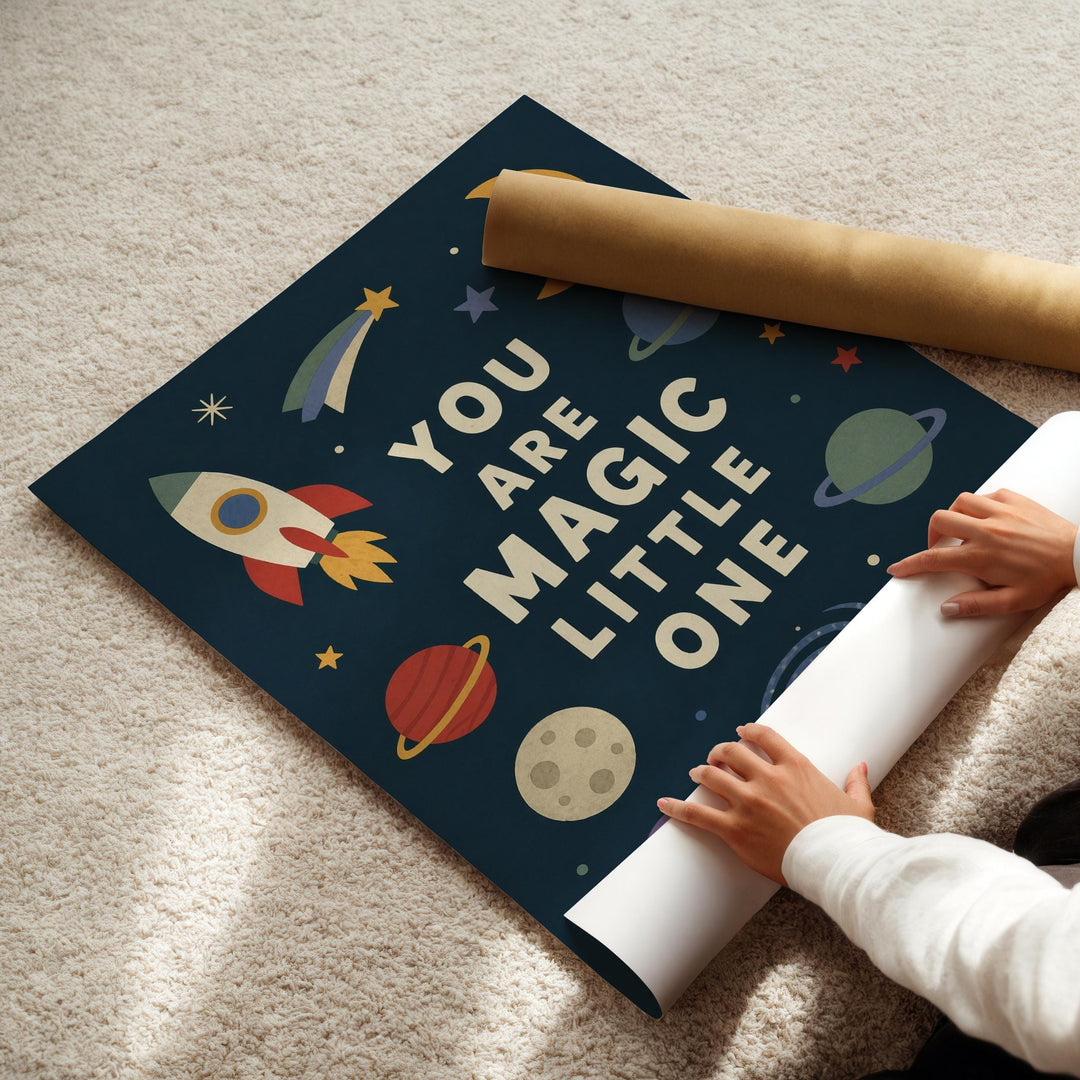A child's hands are seen placing a roll of paper on a poster with a space-themed design, which includes a rocket, planets, and stars.