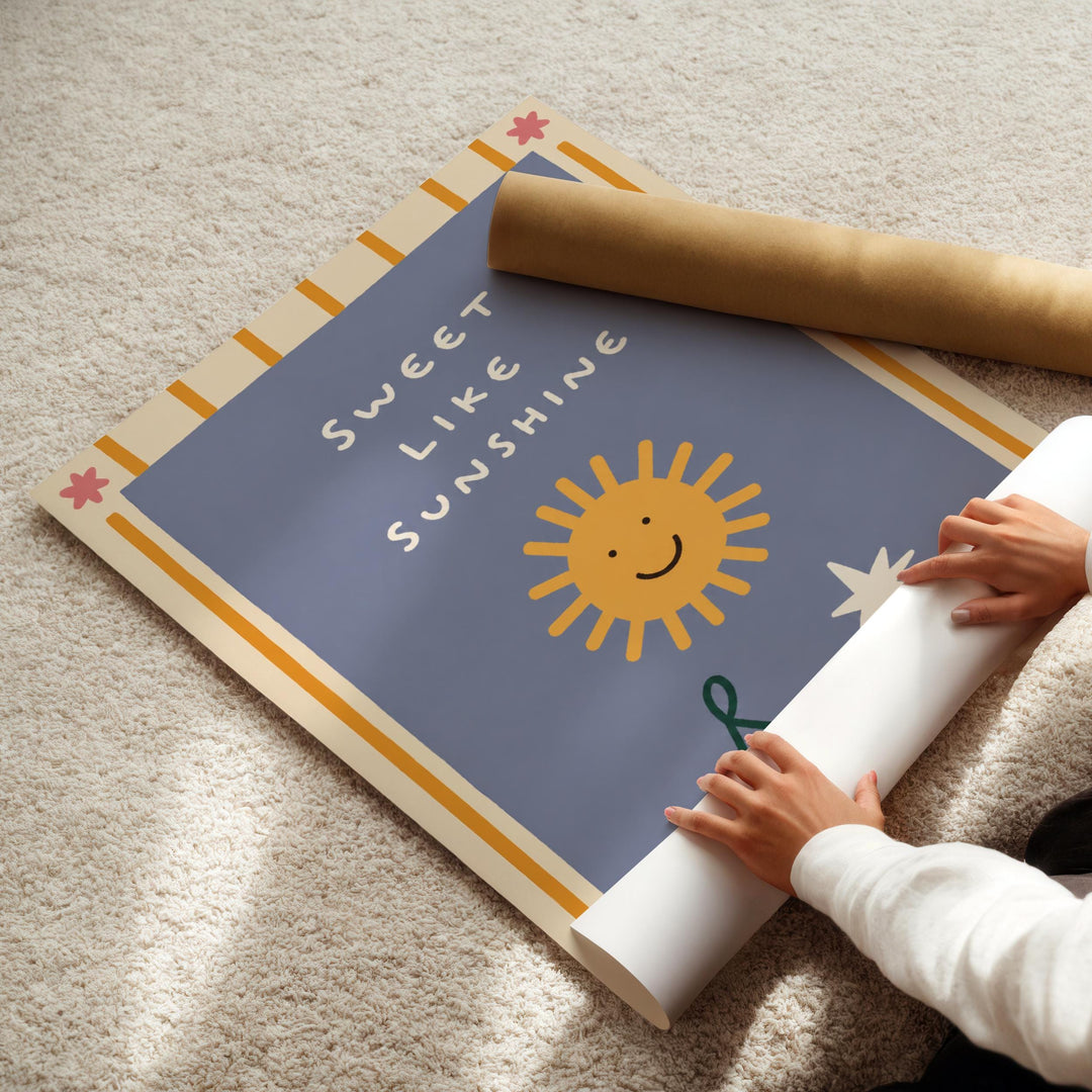 A person's hands are rolling up a poster with a blue background and a sun design, along with the text "Sweet like sunshine".