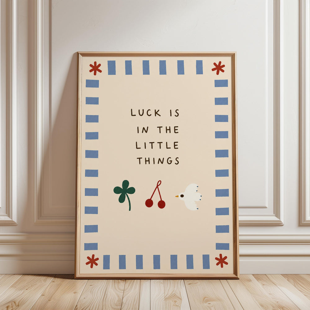 A framed poster with the text "LUCK IS IN THE LITTLE THINGS" and illustrations of a clover, cherries, and a bird.