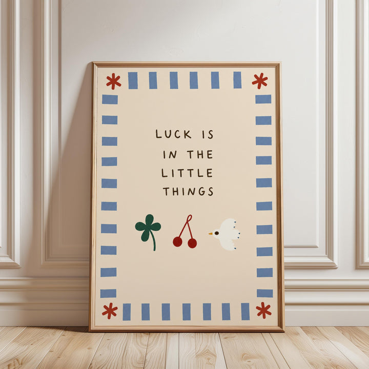 A framed poster with the text "LUCK IS IN THE LITTLE THINGS" and illustrations of a clover, cherries, and a bird.