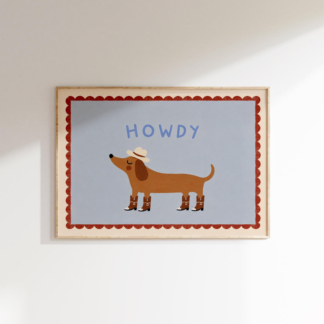 A framed illustration of a dog wearing a cowboy hat and boots, with the word "HOWDY" written above it.