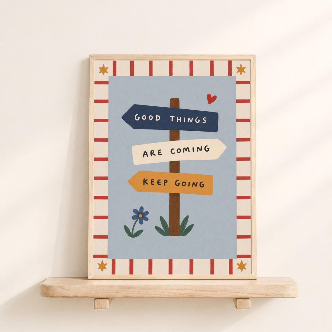The image is a framed poster with a blue background and a border of red and white stripes. The poster features a signpost with three directional signs, each with a different color and text. The signpost reads "GOOD THINGS ARE COMING KEEP GOING".