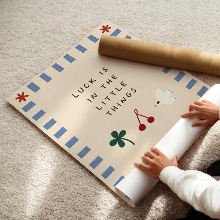 A child's hands are seen rolling up a poster with a message about luck, surrounded by various symbols and designs.