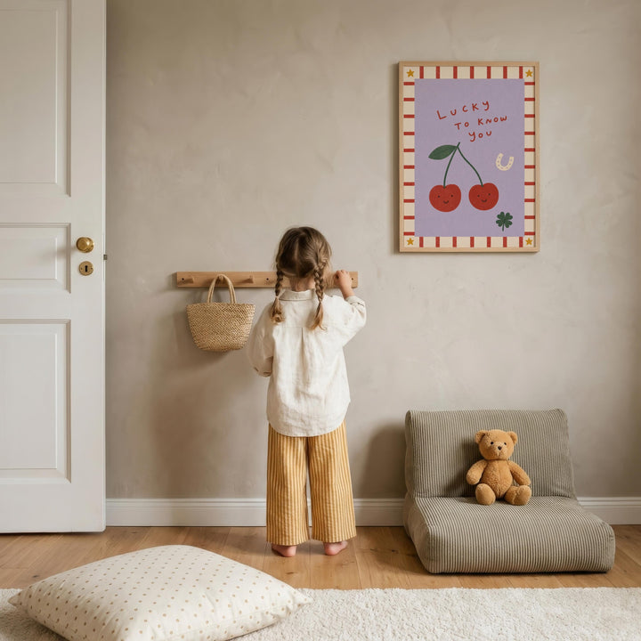 A young girl stands in a cozy room, looking up at a framed poster on the wall that says "Lucky to know you". The room has a comfortable chair, a teddy bear, and a woven basket on a shelf.