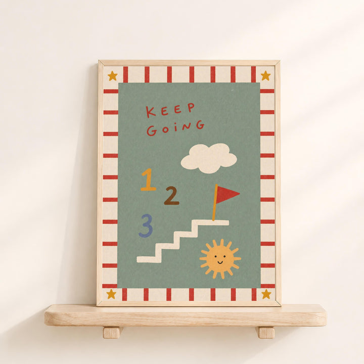 The image is a framed poster with a colorful design featuring a cloud, sun, and stairs. The poster has a motivational message that reads "Keep Going" and includes numbers 1, 2, and 3. The poster is displayed on a wooden shelf against a white wall.