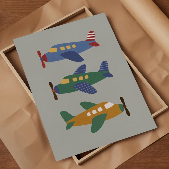 A framed print featuring three colorful airplanes in different positions, with a light brown background.