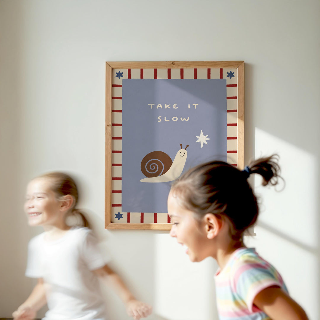 Two young girls are running in a room with a framed poster on the wall that says "TAKE IT SLOW" and features a snail and a star.
