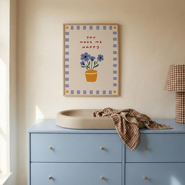 a blue dresser with a white sink, a framed poster with a flower design, and a plaid blanket on top of the dresser.