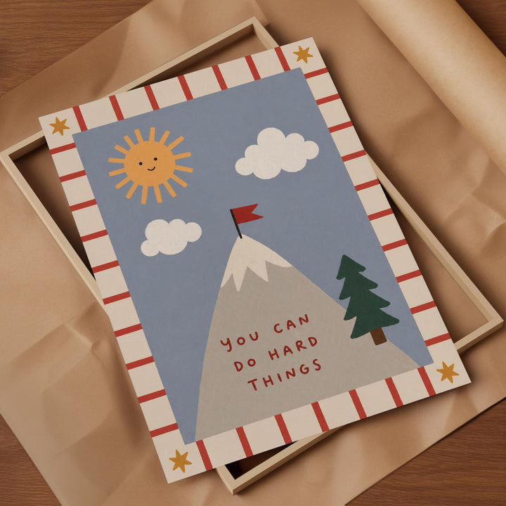The image is a framed print with a mountain, clouds, a flag, and a tree, along with a motivational message.
