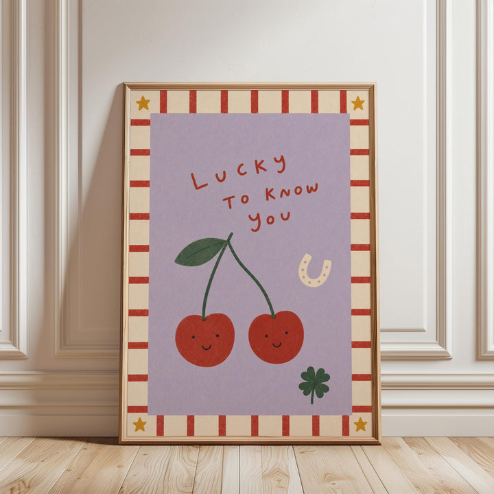 A framed poster with a purple background, featuring two cherries with smiling faces, a horseshoe, and the text "Lucky To Know You" in a playful and whimsical style.