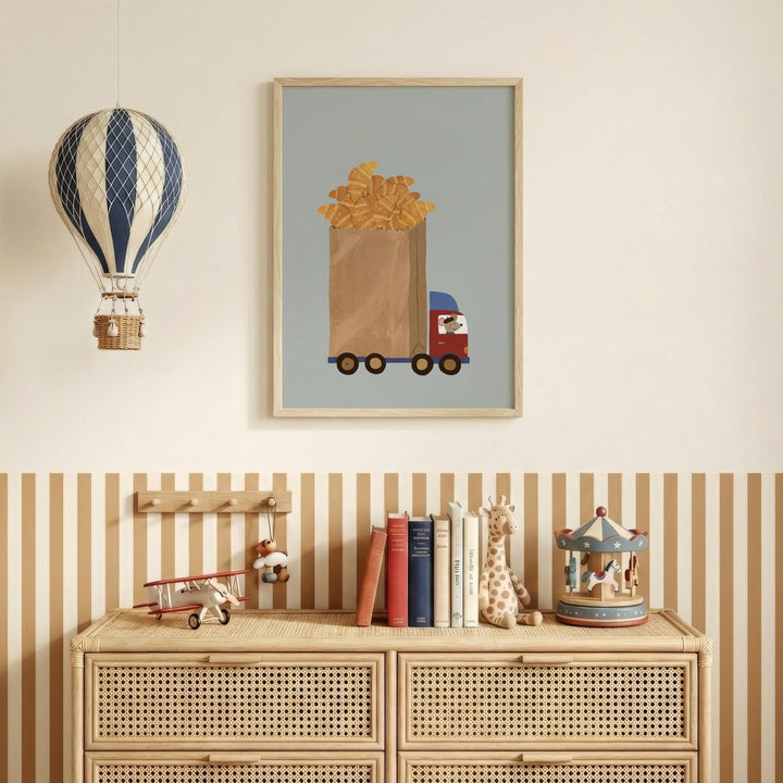 a wooden dresser with a framed picture of a truck carrying a basket of bread, a hot air balloon, and a toy carousel. The dresser also has a collection of books and toys on top of it.