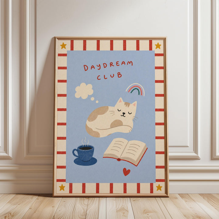 The image is a framed poster with a cat sleeping, a cup of coffee, and a book, all set against a blue background with a red and white border.