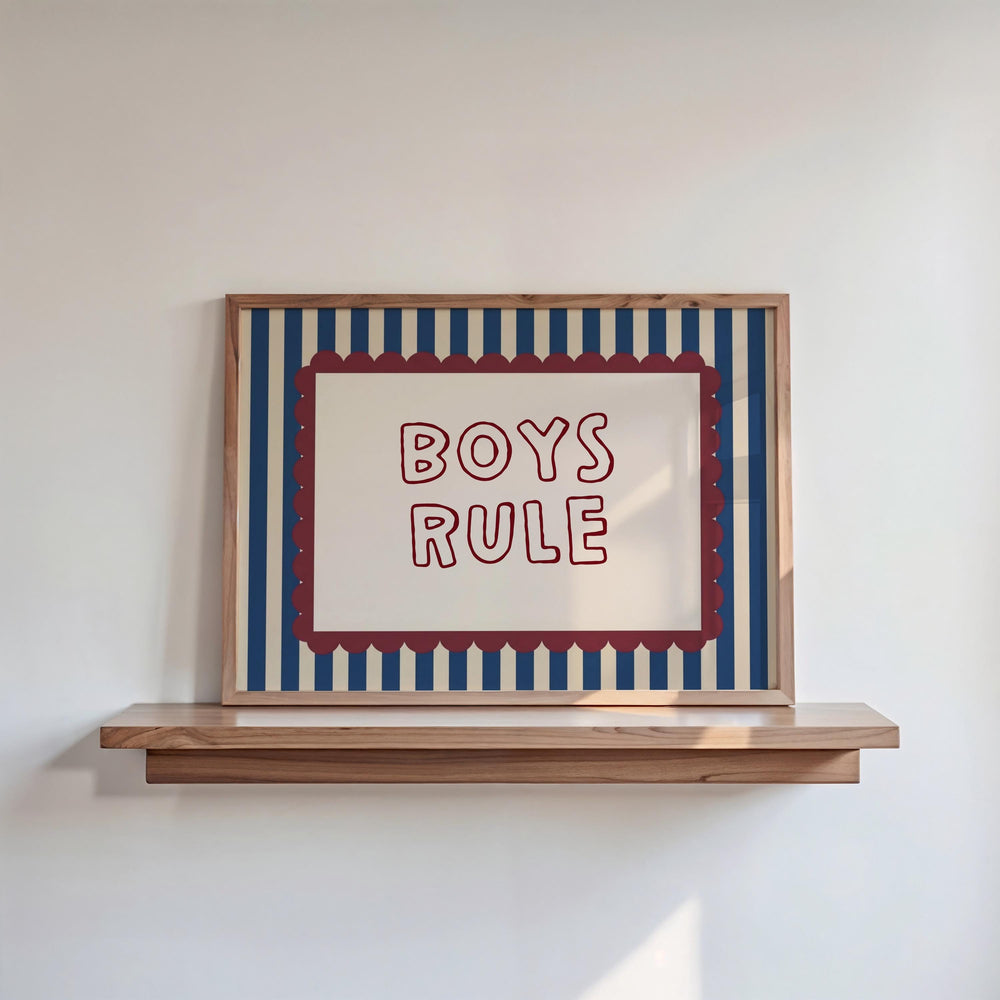 a framed poster with the text "BOYS RULE" displayed on it, mounted on a wooden shelf against a white wall.