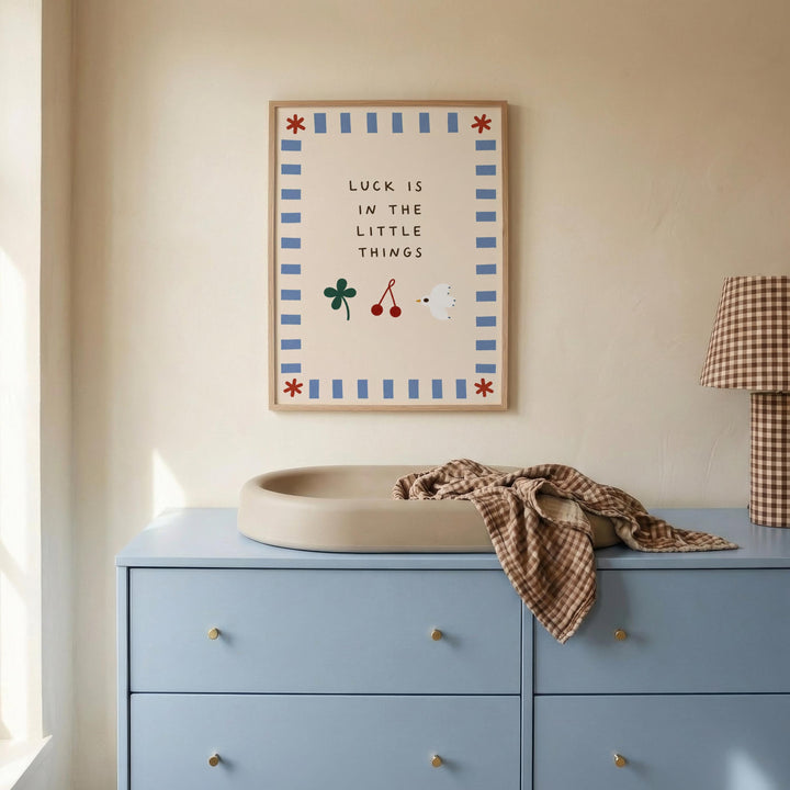 a blue dresser with a white sink on top, and a framed poster with a message about luck is in the little things hanging on the wall above the dresser.