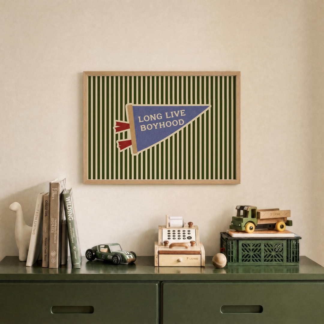 a framed poster with the text "LONG LIVE BOYHOOD" on it, displayed on a wall above a green dresser with various items on it, including books, toys, and a toy car.
