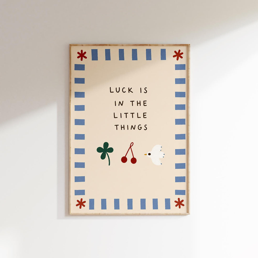 The image is a framed poster with the text "LUCK IS IN THE LITTLE THINGS" and illustrations of a clover, cherries, and a bird.