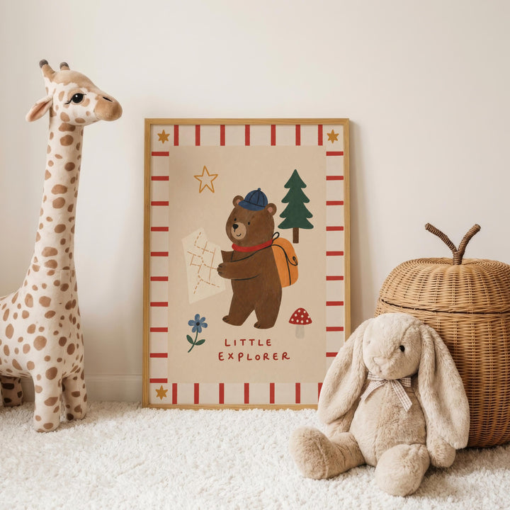 a framed picture of a bear holding a map, surrounded by a giraffe and a stuffed rabbit, all sitting on a white carpet.