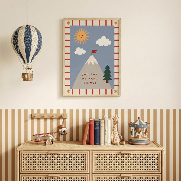 a child's bedroom with a framed poster on the wall that says "You can do hard things", a hot air balloon, a toy airplane, a toy carousel, and a bookshelf with books and toys.