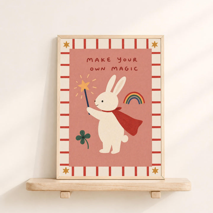 a framed illustration of a white rabbit holding a wand and a rainbow, with the text "MAKE YOUR OWN MAGIC" written above it.