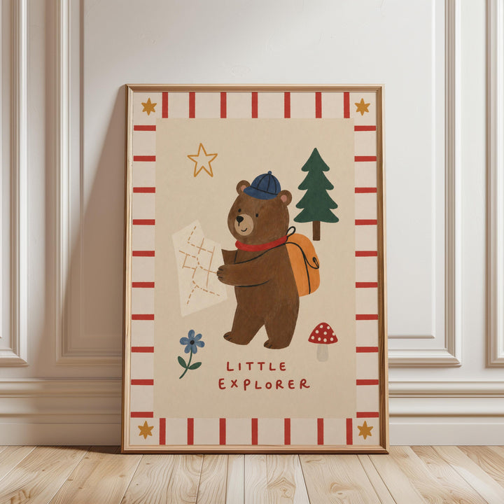 The image is a framed poster featuring a cartoon bear holding a map and a backpack, with the text "Little Explorer" below the bear.