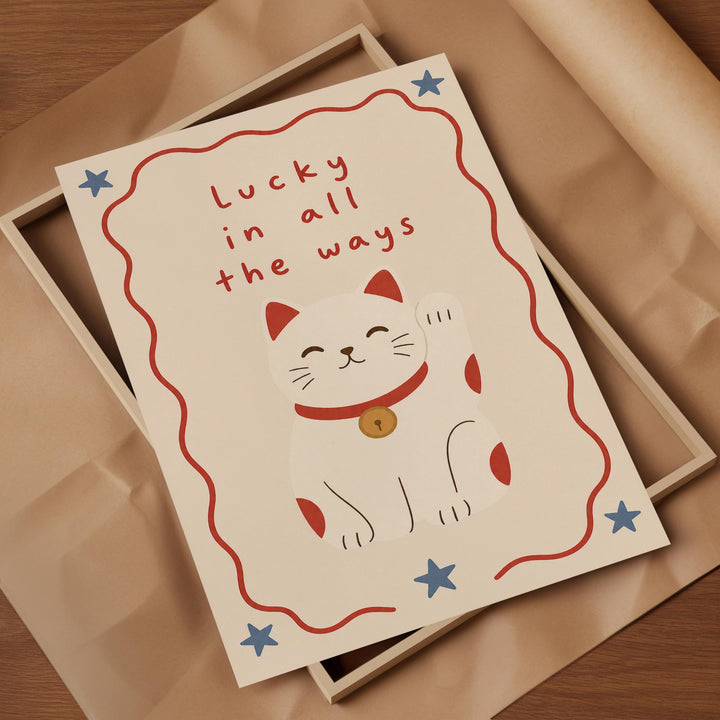 A framed card with a white cat illustration and the text "Lucky in all the ways" written on it.