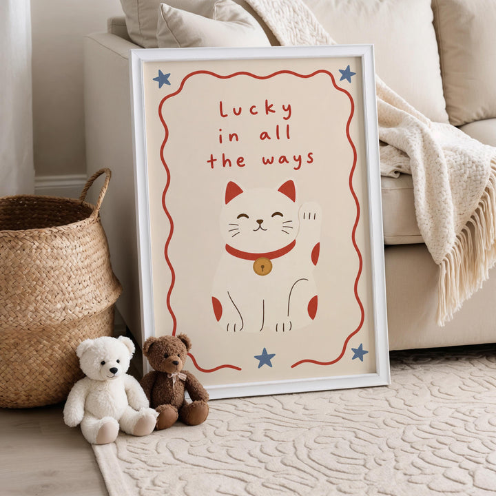 A framed poster with a cat illustration and the text "Lucky in all the ways" is displayed on a wall, accompanied by two stuffed animals, a teddy bear and a brown bear, sitting on a rug next to a woven basket.