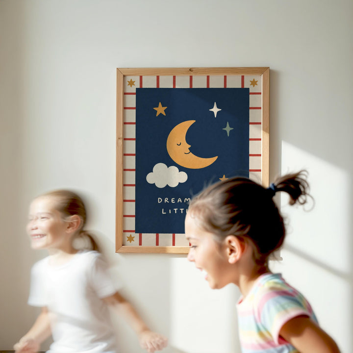 Two young girls are running in a room with a framed poster of a crescent moon and stars on the wall.