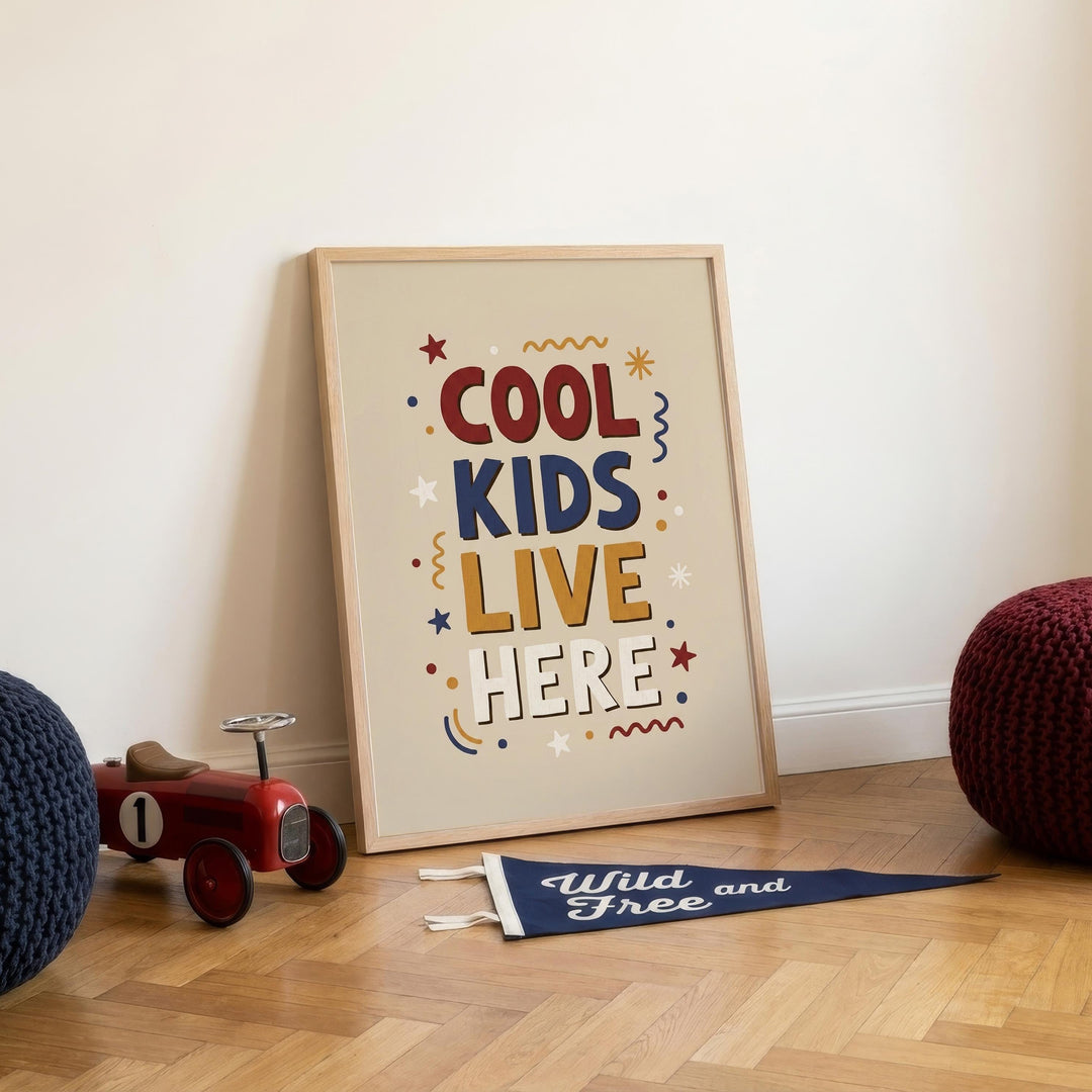 a framed poster with the text "COOL KIDS LIVE HERE" and colorful decorative elements, placed on a wooden floor next to a toy tractor and a blue flag.
