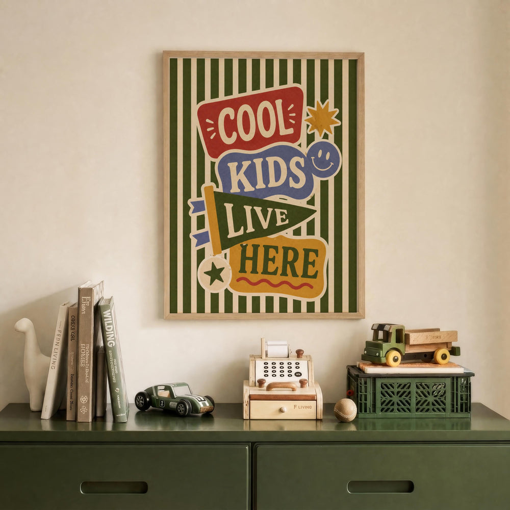 a wall with a framed poster that says "Cool Kids Live Here", along with various toys and books on a green dresser below it.