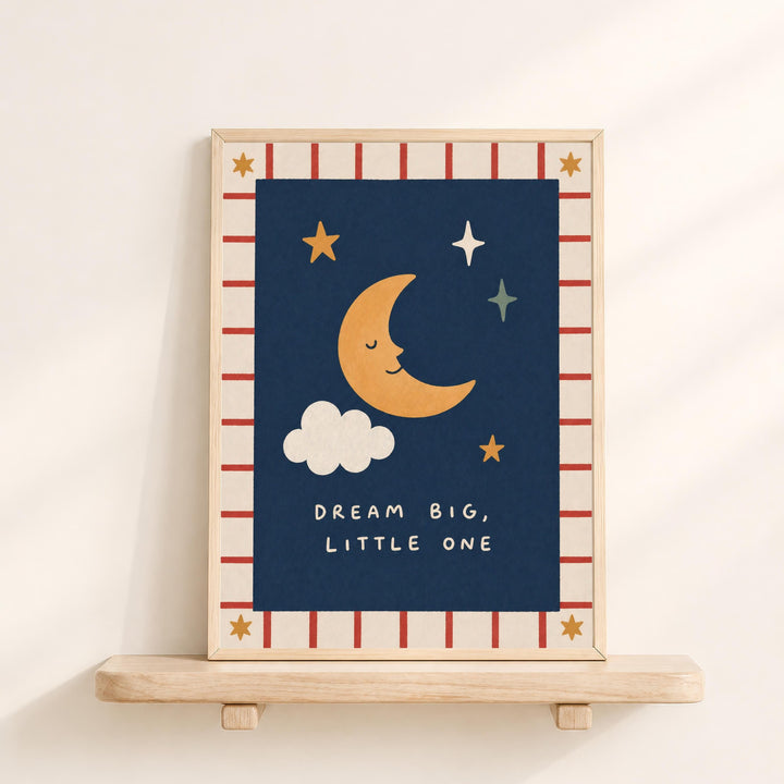 a framed illustration of a crescent moon, stars, and clouds on a blue background, with the text "DREAM BIG, LITTLE ONE" written below.