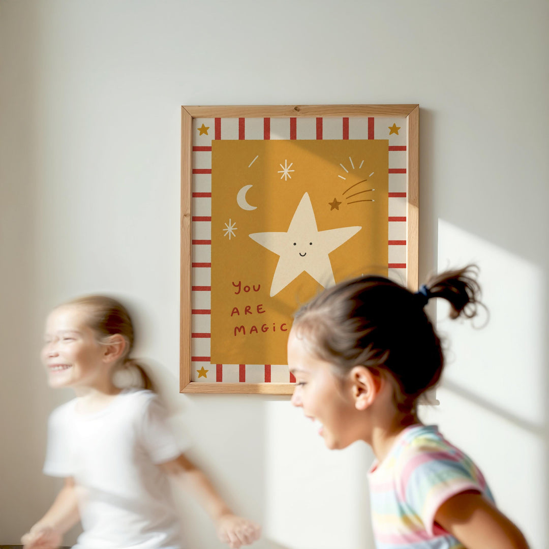 Two young girls are running in front of a framed picture with a star and a message about being magical.