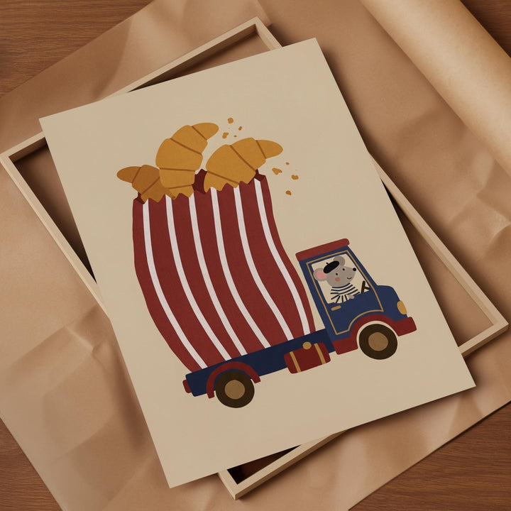 A framed illustration of a cartoon mouse riding a truck carrying a large bucket filled with golden-brown croissants.