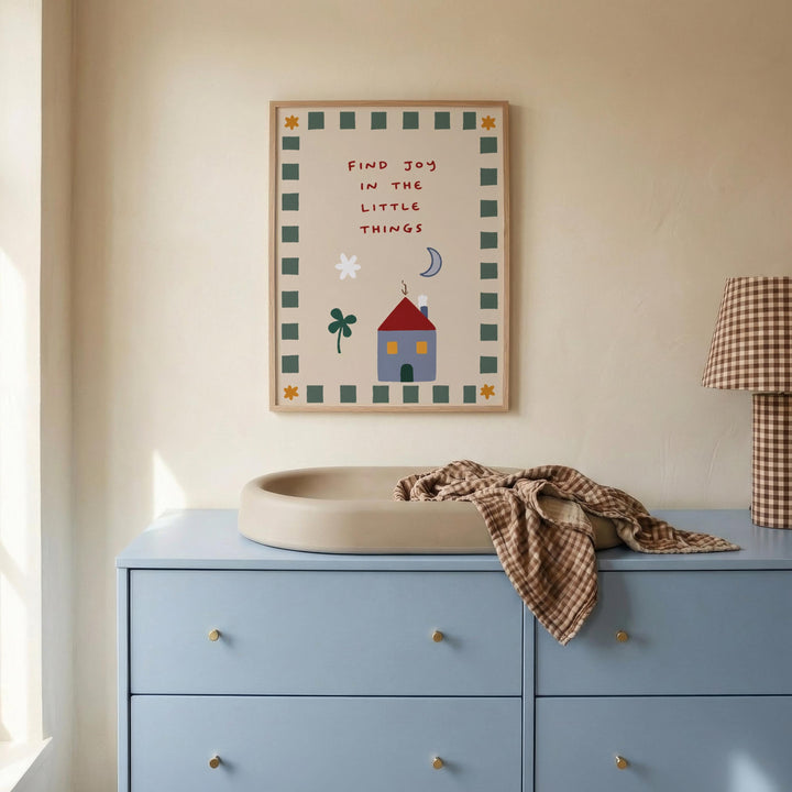 a blue dresser with a white sink on top, and a framed poster with a house and a tree on the wall above it.