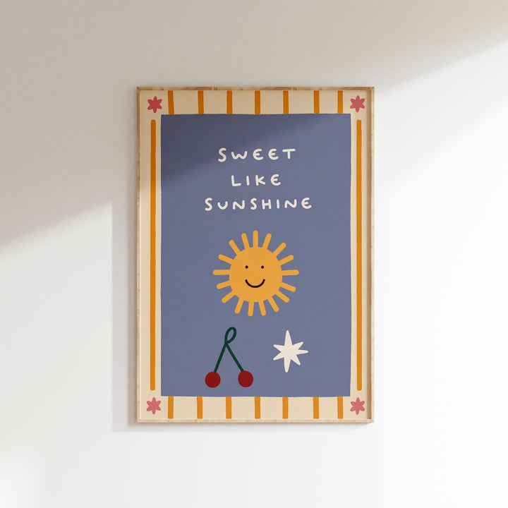 The image is a framed poster with a blue background, featuring a cheerful sun, cherries, and a star. The text on the poster reads "Sweet like sunshine".