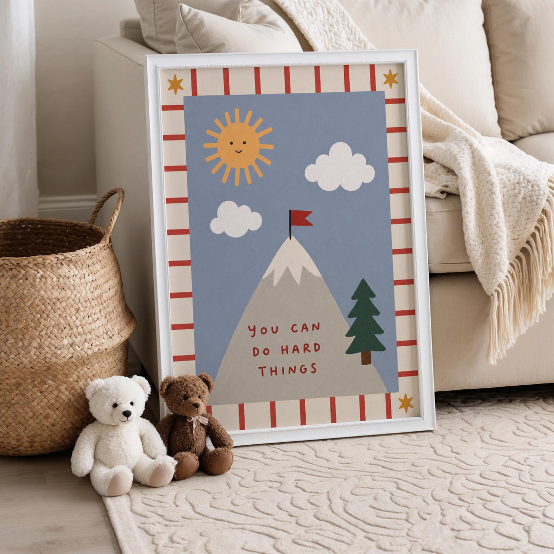 A framed poster with a mountain and clouds, along with a teddy bear and a stuffed animal, is displayed on a wall in a cozy living room setting.