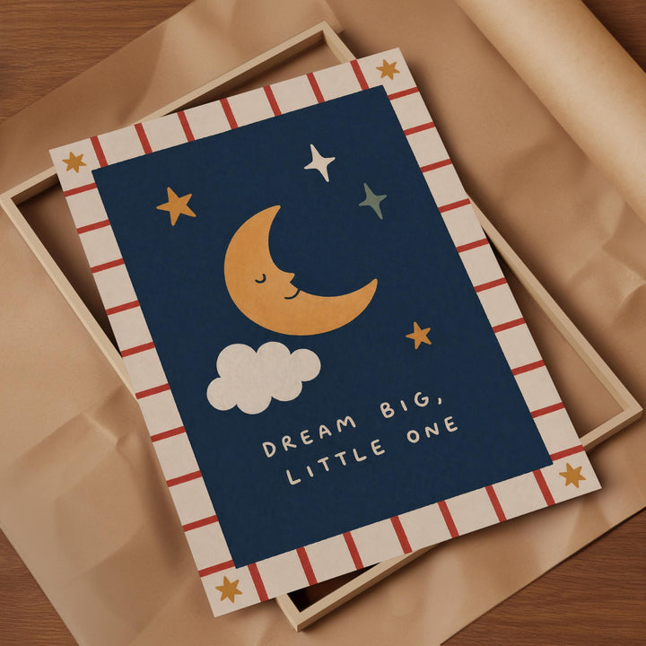 a framed print with a crescent moon, stars, and a cloud, along with the text "Dream Big, Little One" written on it.