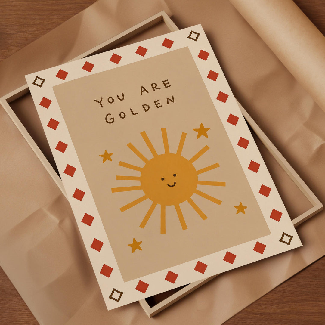 A greeting card with a sun and stars design, placed on a brown surface.