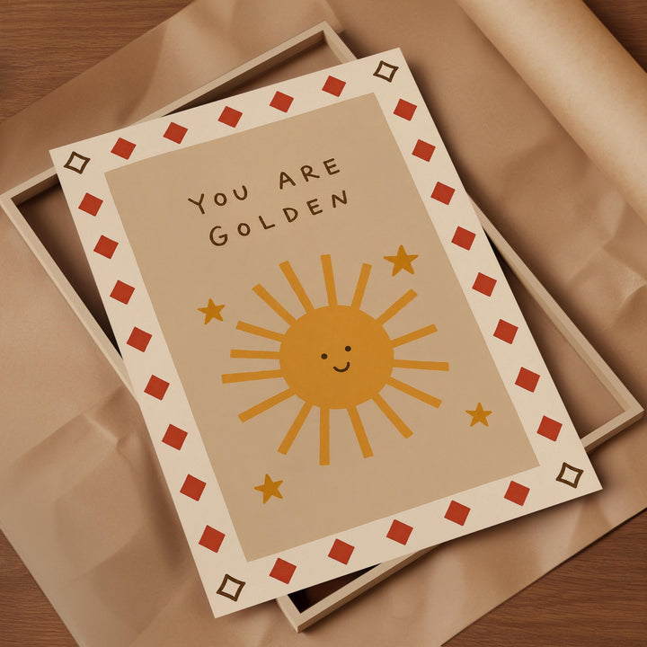 A greeting card with a sun and stars design, placed on a brown surface.