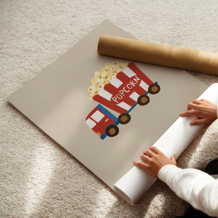 A person's hands are holding a roll of paper, which appears to be a poster or artwork featuring a red and white truck with a large popcorn bucket.