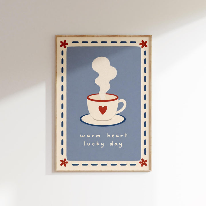 A framed illustration of a steaming cup of coffee with a heart symbol, accompanied by the text "Warm heart lucky day" in a decorative border.