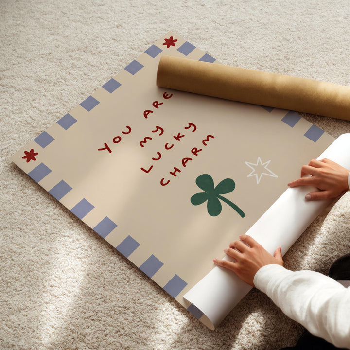 A person's hands are holding a roll of paper, which appears to be a poster or sign with a message about luck and charm.