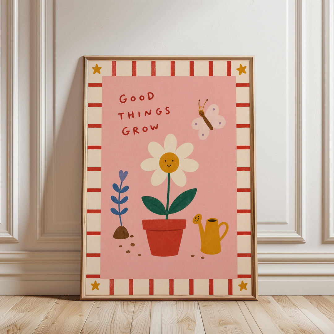 A framed poster with a pink background, featuring a smiling flower, a watering can, and a butterfly. The text "Good things grow" is written above the flower.