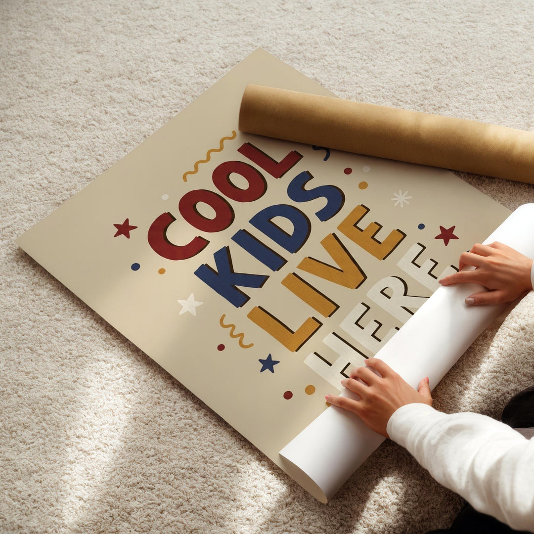 A person's hands are rolling up a poster with the text "COOL KIDS LIVE HERE" on it.