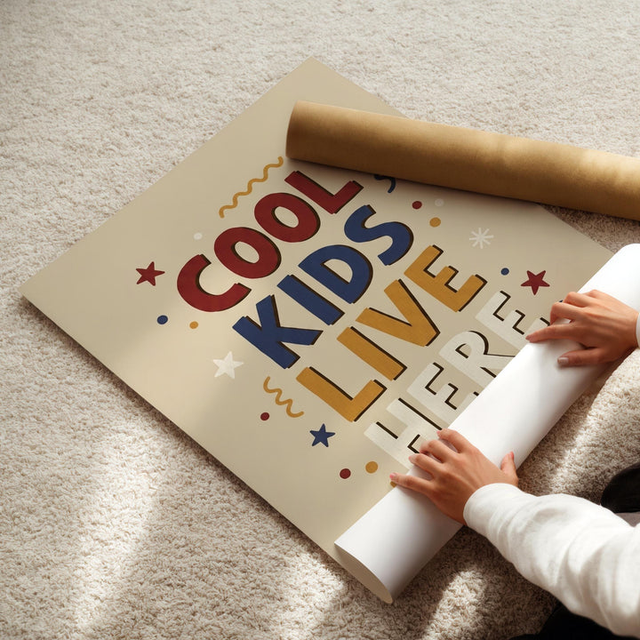 A person's hands are rolling up a poster with the text "COOL KIDS LIVE HERE" on it.