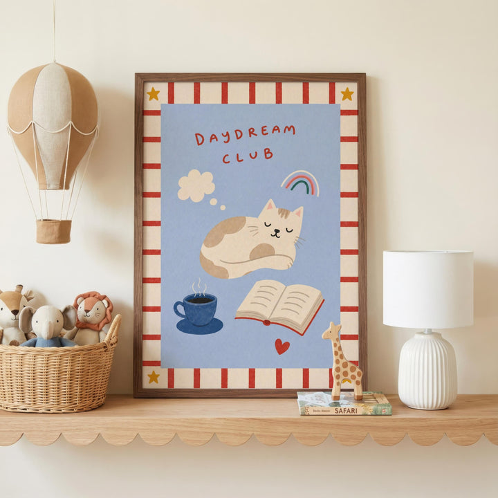 a framed poster with a cat illustration, a hot air balloon, a cup of coffee, a book, a giraffe, and a basket of stuffed animals on a shelf.