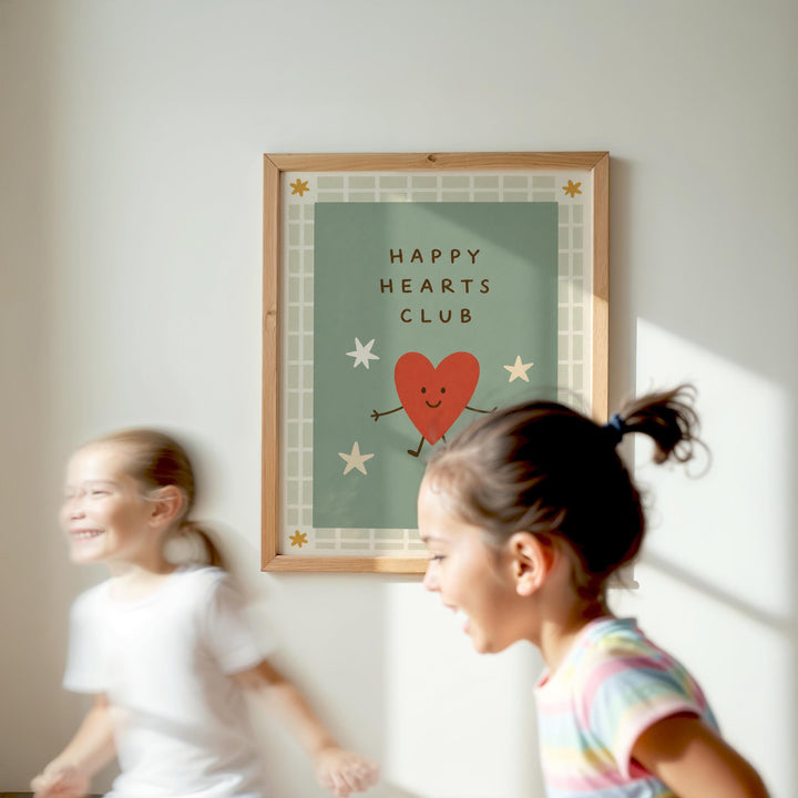 Two young girls are running in front of a framed poster with a heart and stars design, which says "Happy Hearts Club".