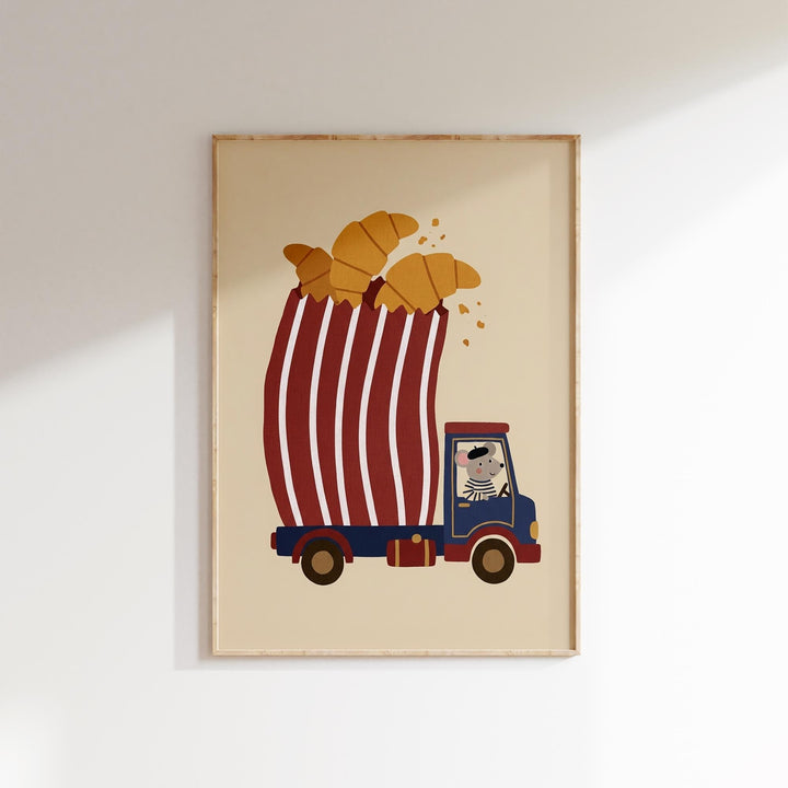 A framed illustration depicting a cartoon character riding a truck with a large red and white striped canopy, carrying a stack of golden-brown croissants.