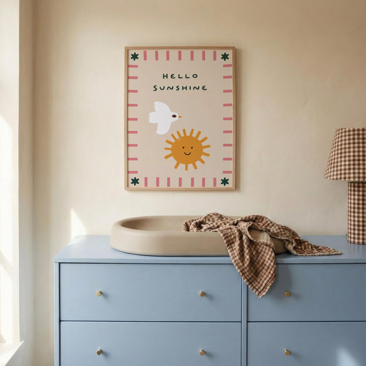 a blue dresser with a white sink on top, and a framed poster with a cartoon sun and bird on the wall above it.