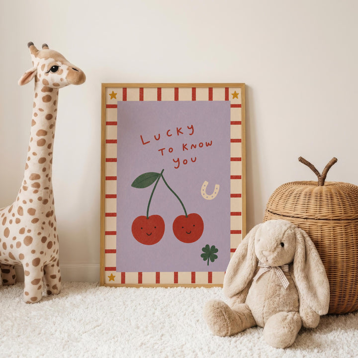 a giraffe, a stuffed rabbit, and a wicker basket, all placed on a white carpet. In the background, there is a framed poster with a cartoon illustration of cherries and a horseshoe.