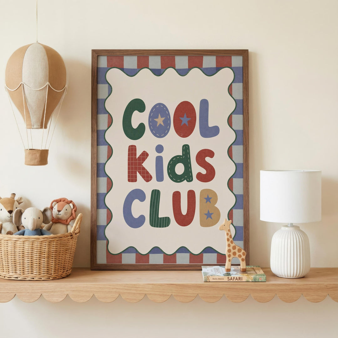 a framed poster with the text "Cool Kids Club" on it, placed on a shelf next to a basket of stuffed animals and a white lamp.
